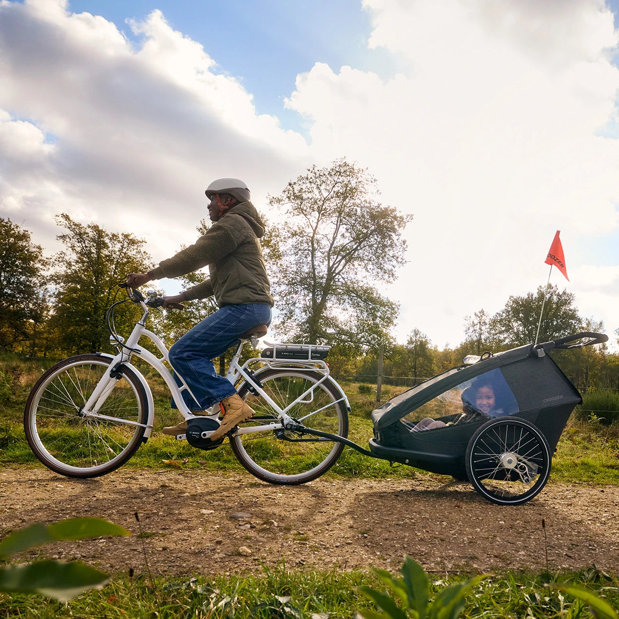Fahrrad fahrende Mutter unterwegs mit Kind und Hund im modularen Croozer Yuuna